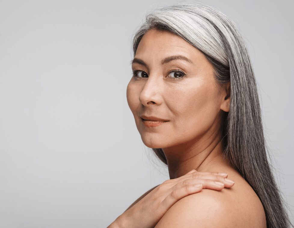 Confident woman with long gray hair and smooth skin.