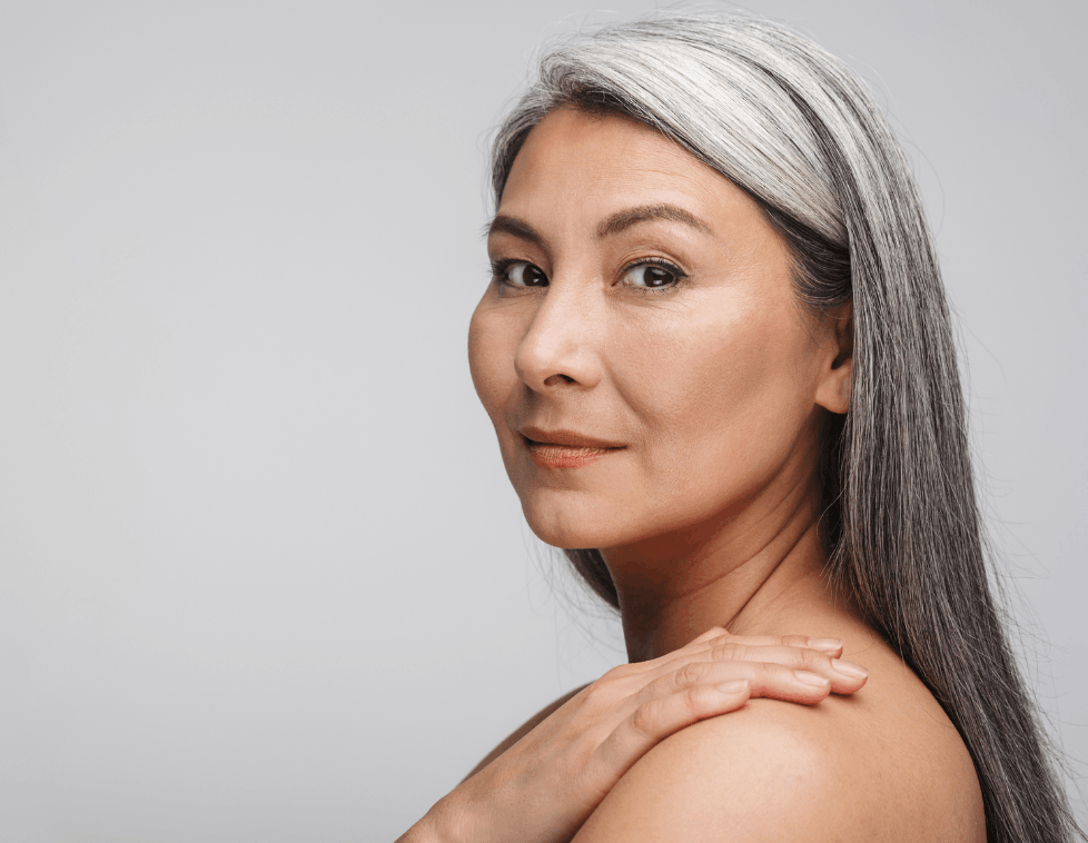 Confident woman with long gray hair and smooth skin.