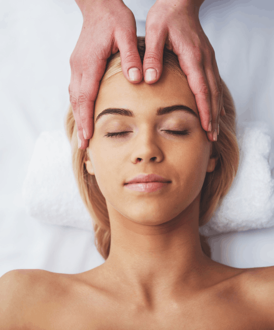 A woman receiving a relaxing head massage with eyes closed.