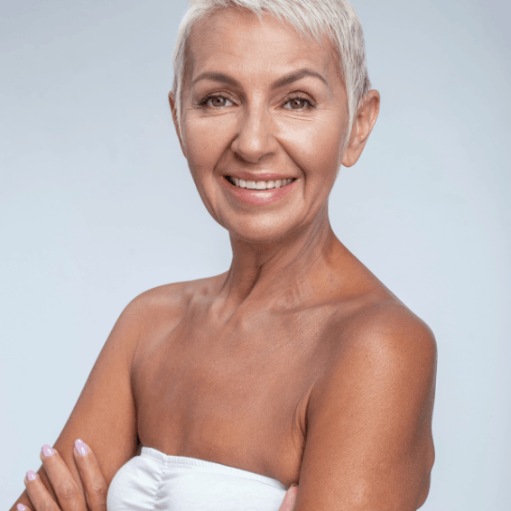 Smiling mature woman with short gray hair against a light background.