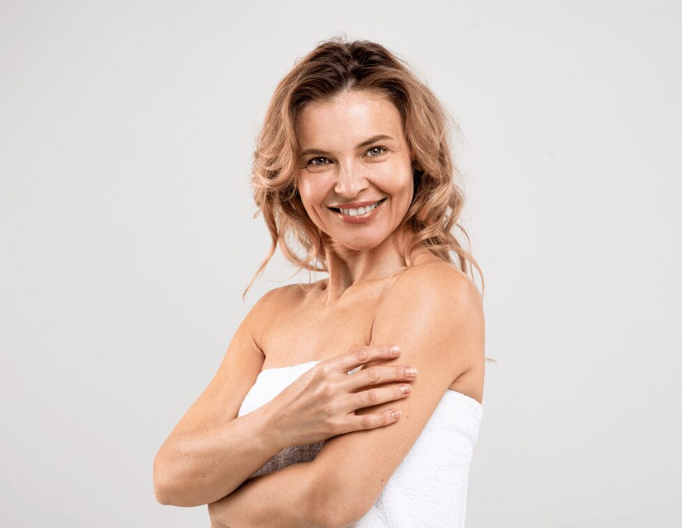Smiling woman with wavy blonde hair and bare shoulders.