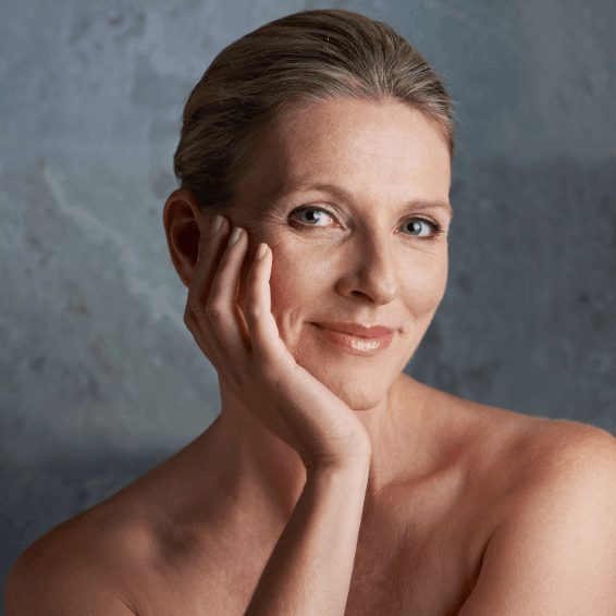 Portrait of a serene woman with natural makeup and hand resting on face.