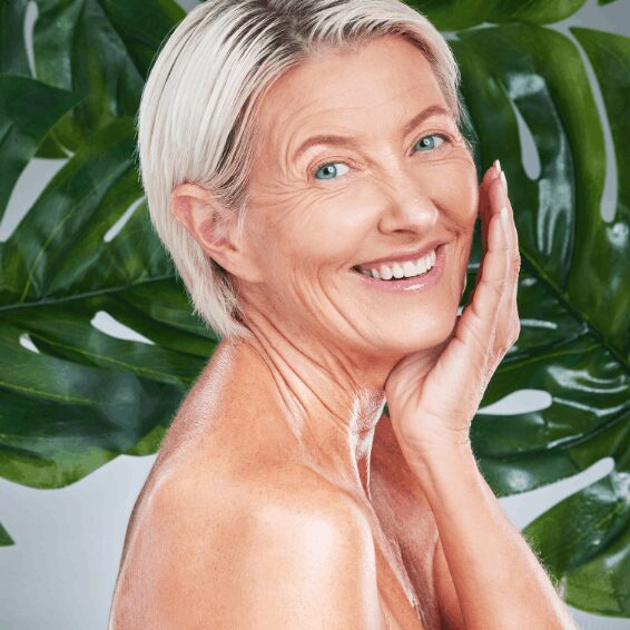 Smiling mature woman with silver hair and clear skin, posing gracefully.