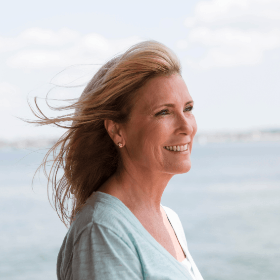Smiling woman enjoying a breezy day by the seaside.
