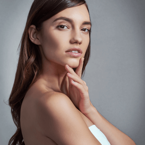 A thoughtful young woman with long hair poses against a gray background.