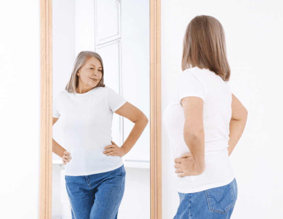 Woman checking her posture in the mirror, hands on hips.