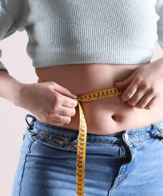 Person measuring their waist with a yellow tape measure.