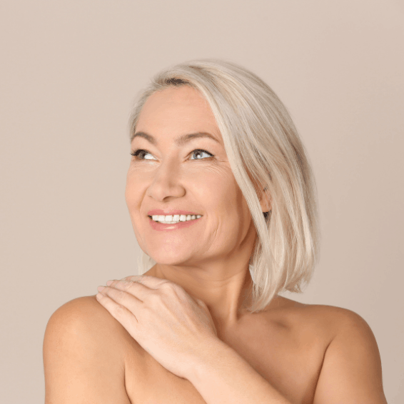 Smiling mature woman with short blonde hair against a beige background.