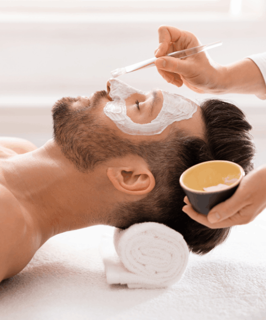 Man receiving a facial mask treatment at a spa.
