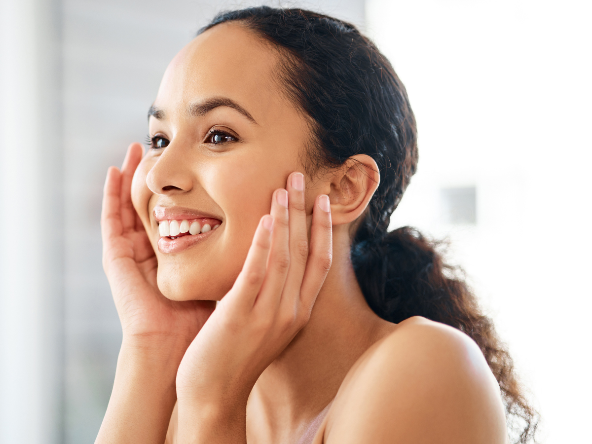Smiling woman gently touching her face, radiating happiness.