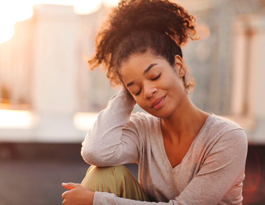 Peaceful young woman relaxing with eyes closed outdoors.