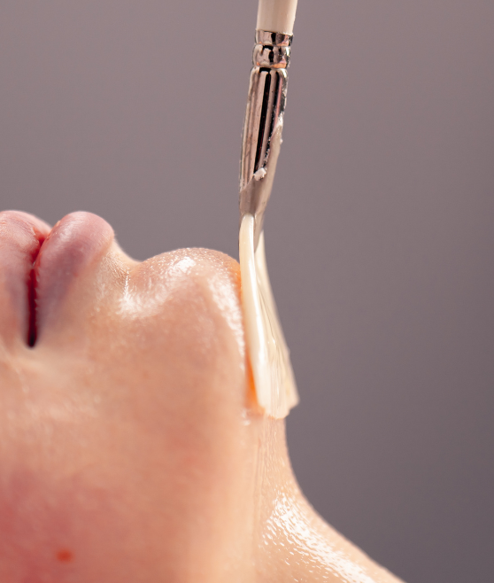 Close-up of a facial treatment brush applying serum to skin.