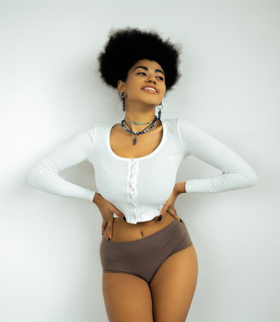 Confident woman posing in casual white top and brown shorts.