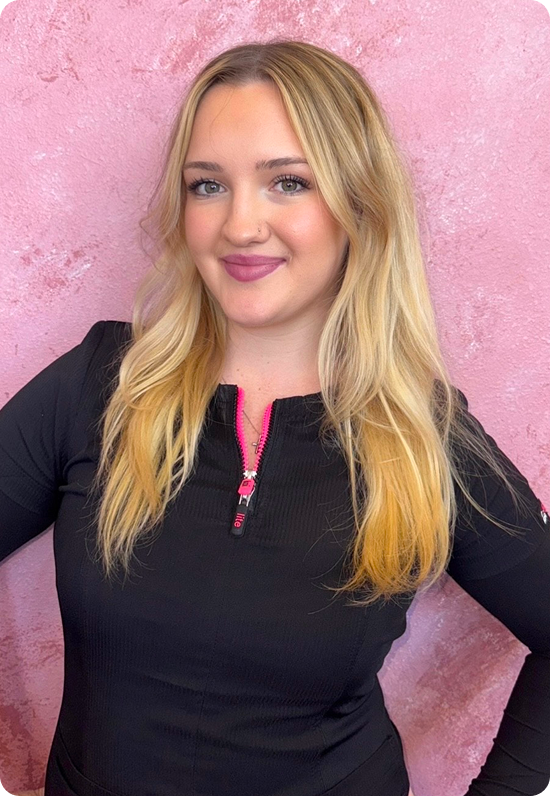 Young woman with blonde hair smiling against a pink background.